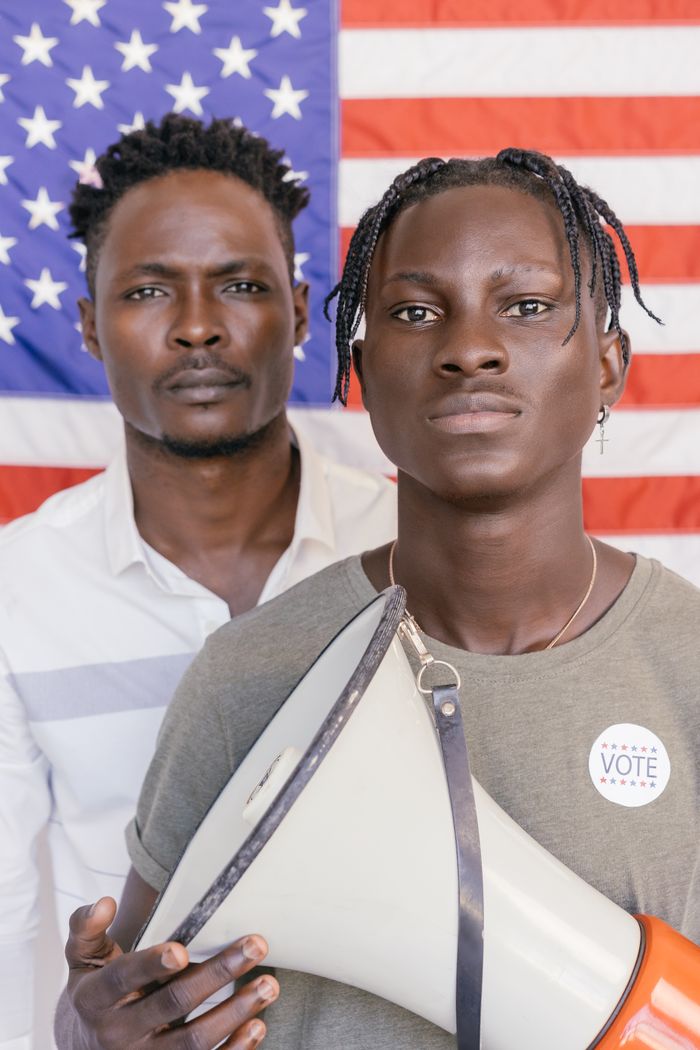 Services Two African American men holding a megaphone with U.S. flag in the background, symbolizing activism.