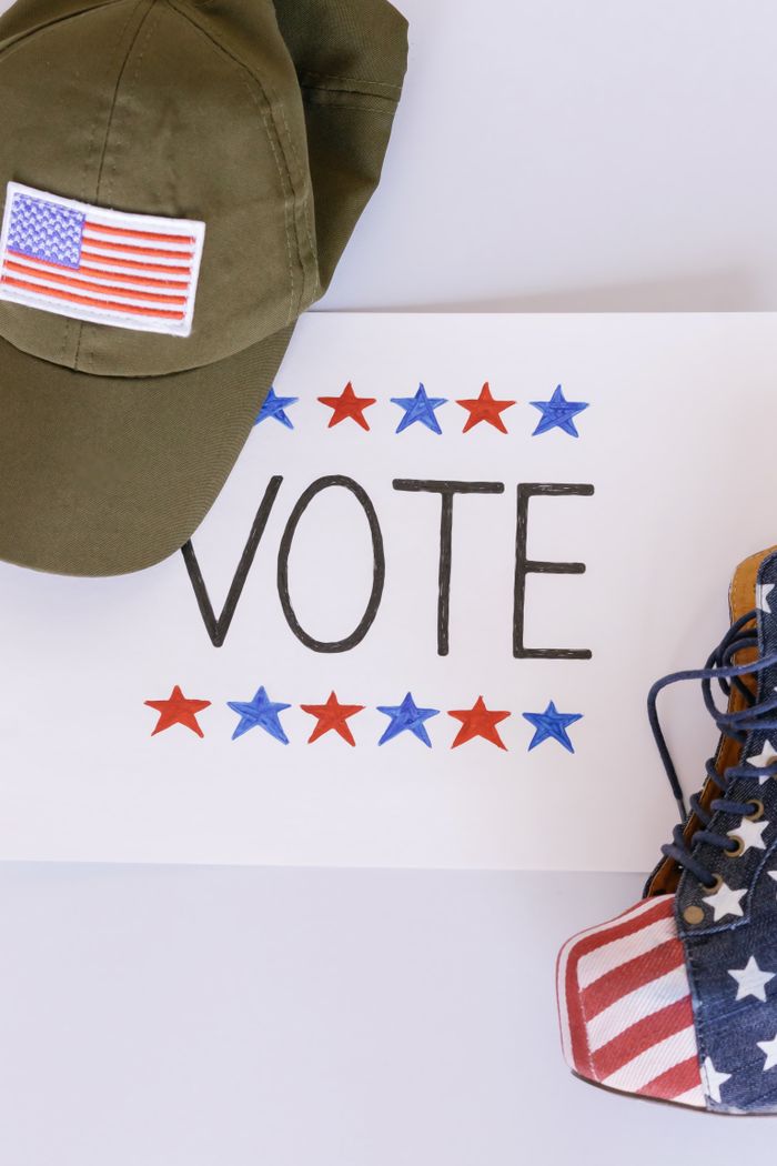 Flat lay of a cap and boots with American flag theme next to VOTE sign.